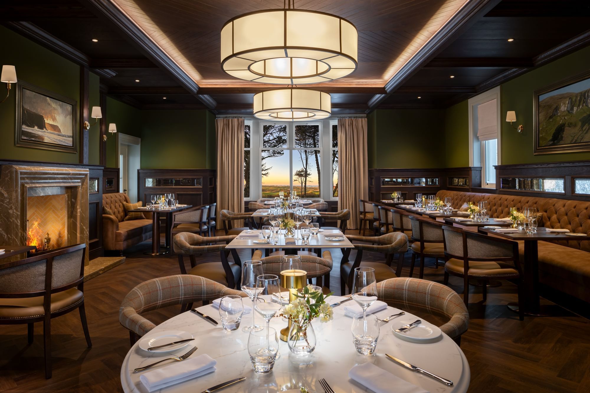 Elegant dining room at Dunluce Lodge, with a cozy fireplace, polished tables, and a large window overlooking the grounds