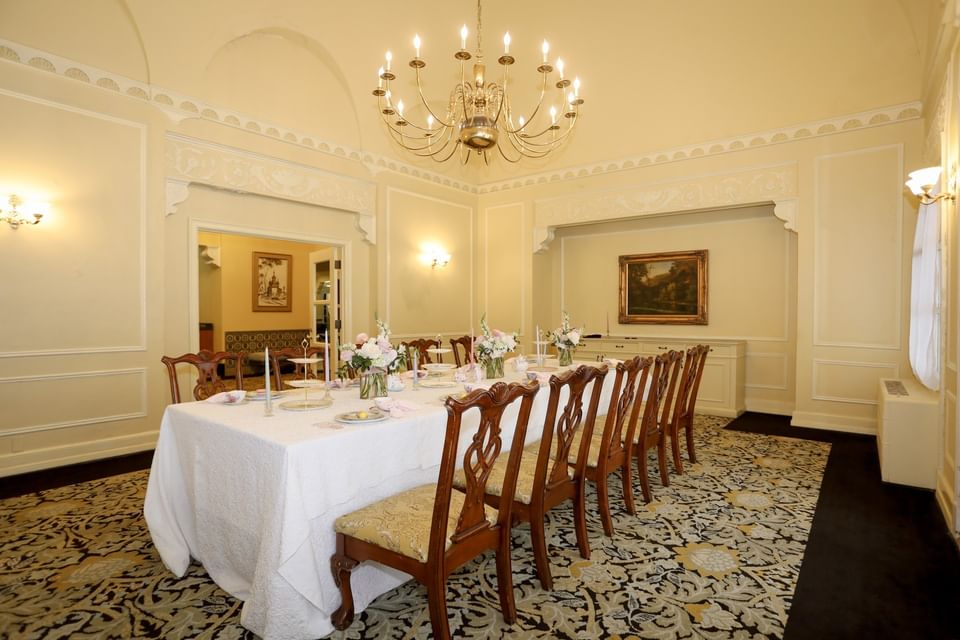 High-back chairs by a long white table under a gold chandelier in Boardroom at the Arlington Resort Hotel & Spa