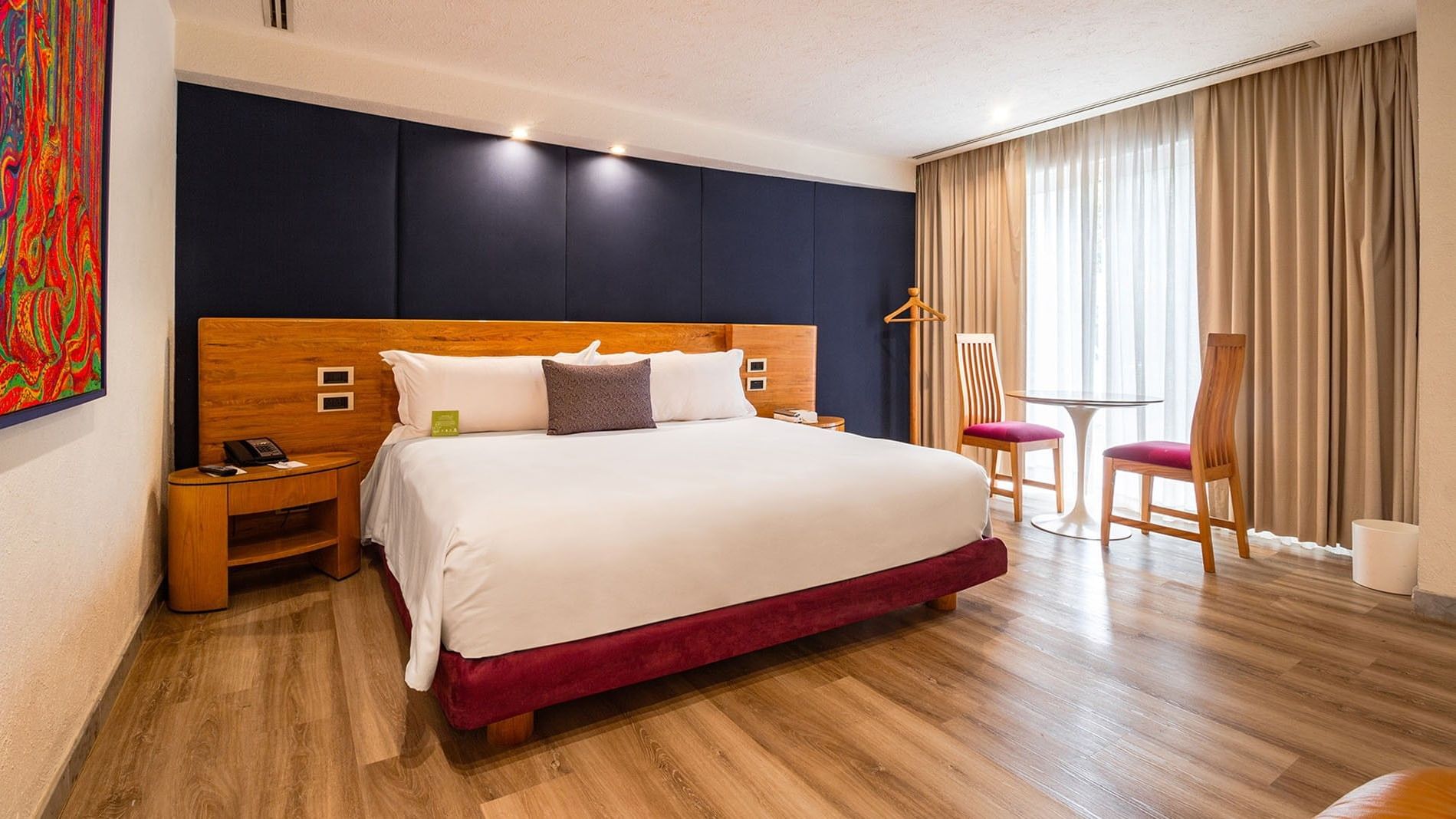 King Camichin Suite including a king bed, wooden floors, and a small dining set at Camino Real Guadalajara