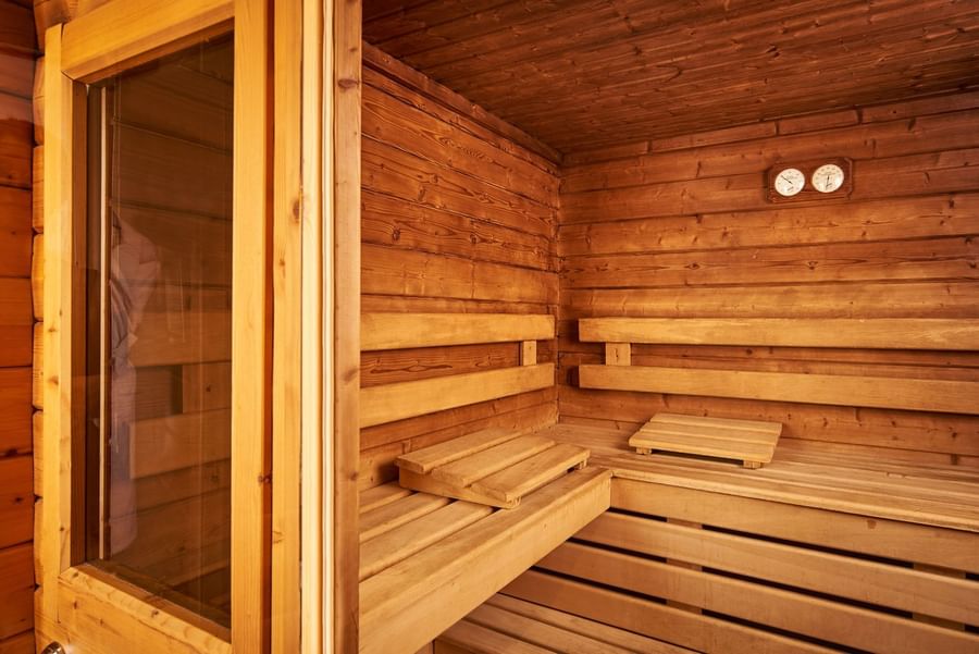 Interior of a wooden sauna with thermometer placed by benches under warm ambient lighting at Hotel Westminster Paris