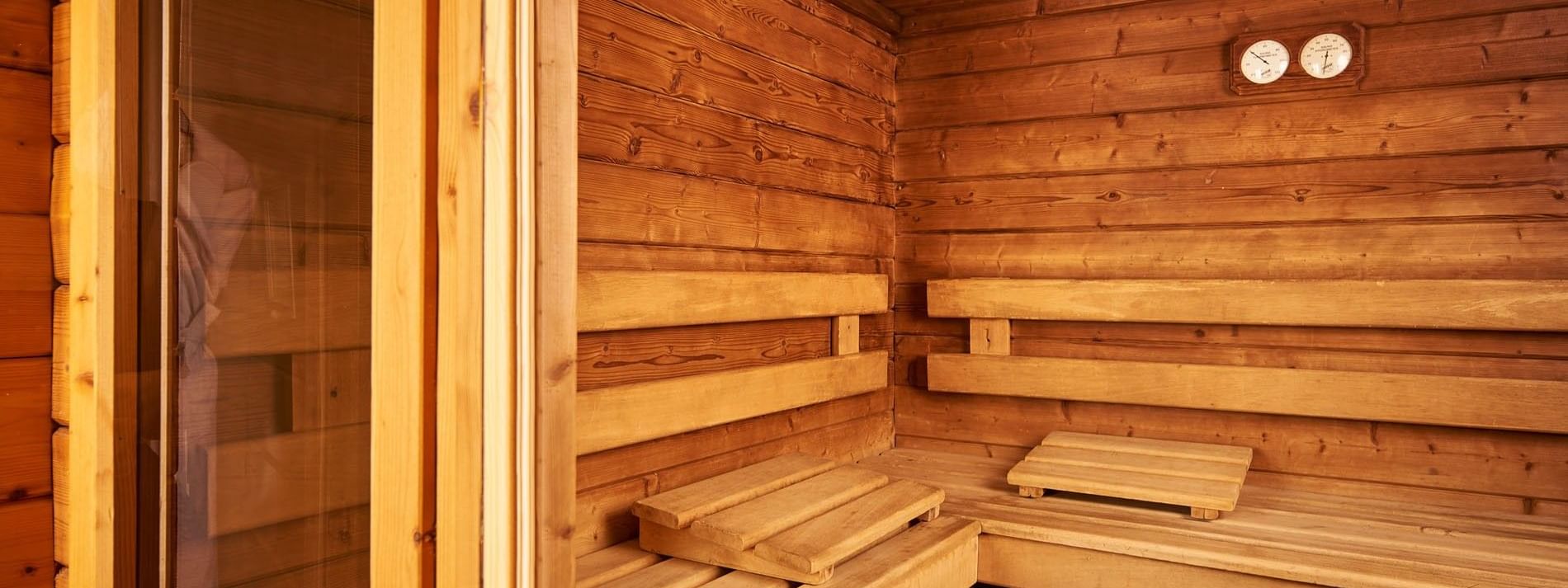 Interior of a wooden sauna with thermometer placed by benches under warm ambient lighting at Hotel Westminster Paris
