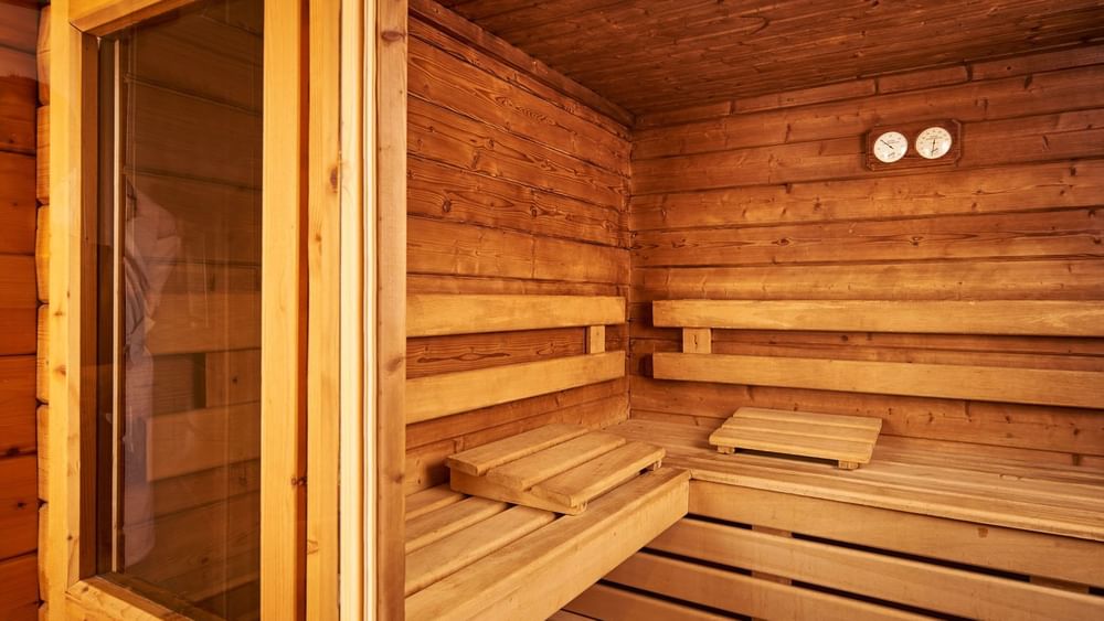 Interior of a wooden sauna with thermometer placed by benches under warm ambient lighting at Hotel Westminster Paris