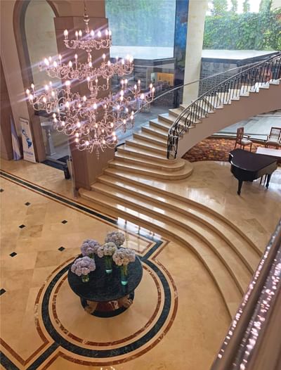 Elegante interior del área del lobby con piano y escalera en el Hotel Dann Carlton Medellín