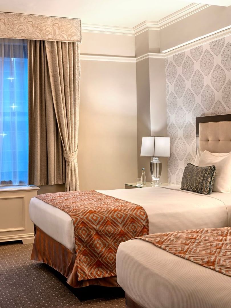 Twin beds facing work desk area with patterned accent walls in Premier City View double beds at Warwick New York