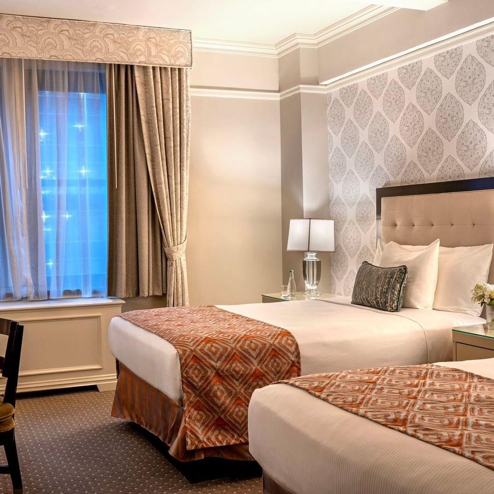 Twin beds facing work desk area with patterned accent walls in Premier City View double beds at Warwick New York