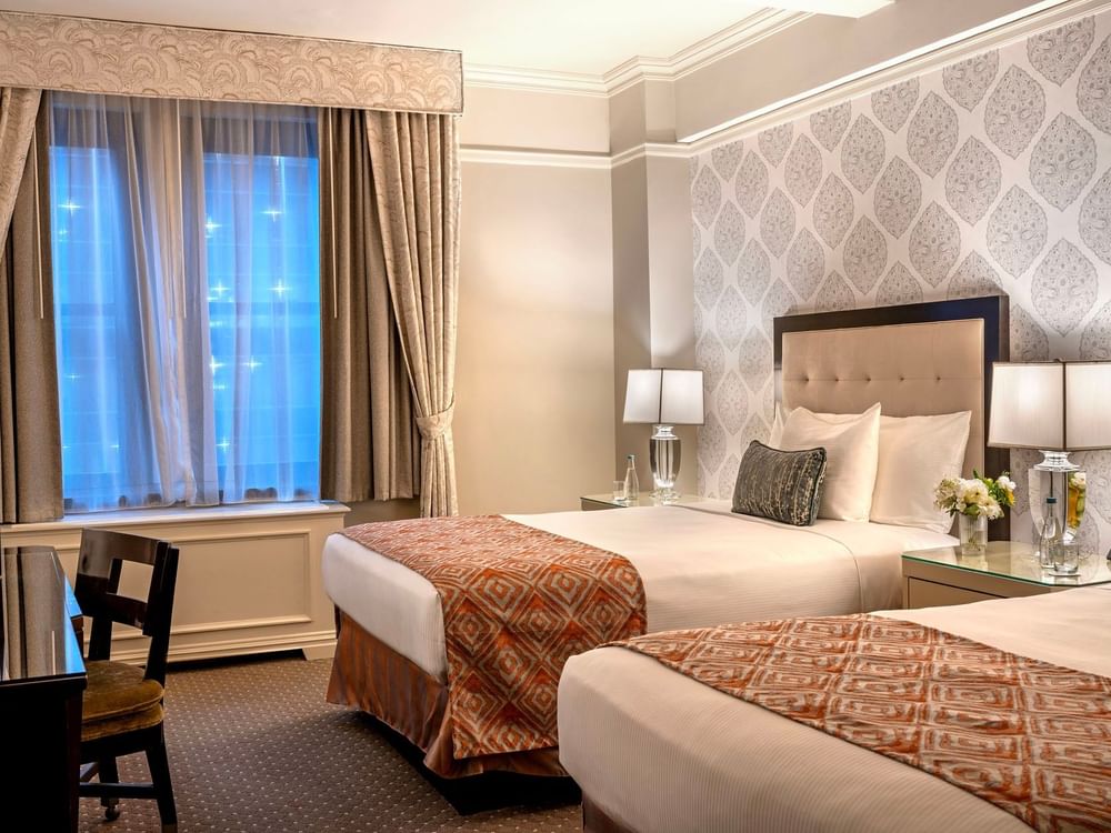 Two twin beds between table lamps and work desk area in Premier City View 2 Double Beds at Warwick New York