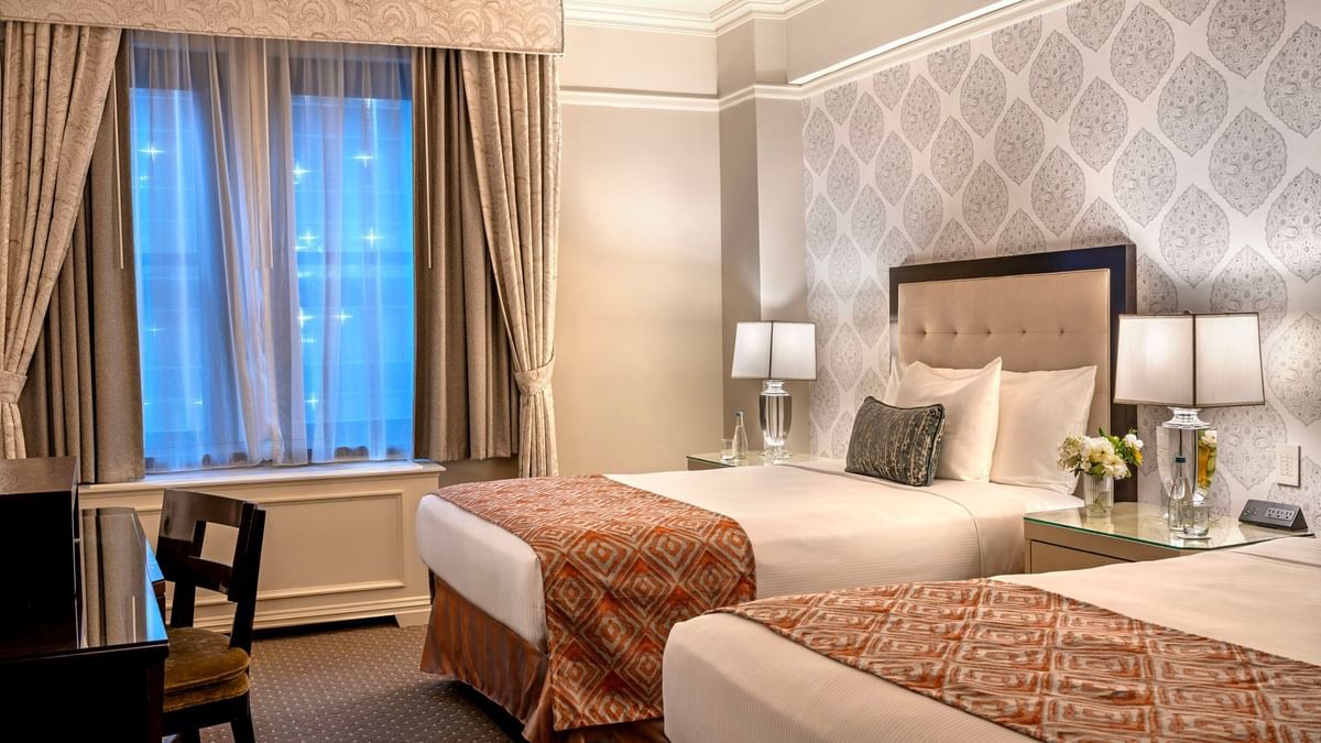 Twin beds facing work desk area with patterned accent walls in Premier City View double beds at Warwick New York