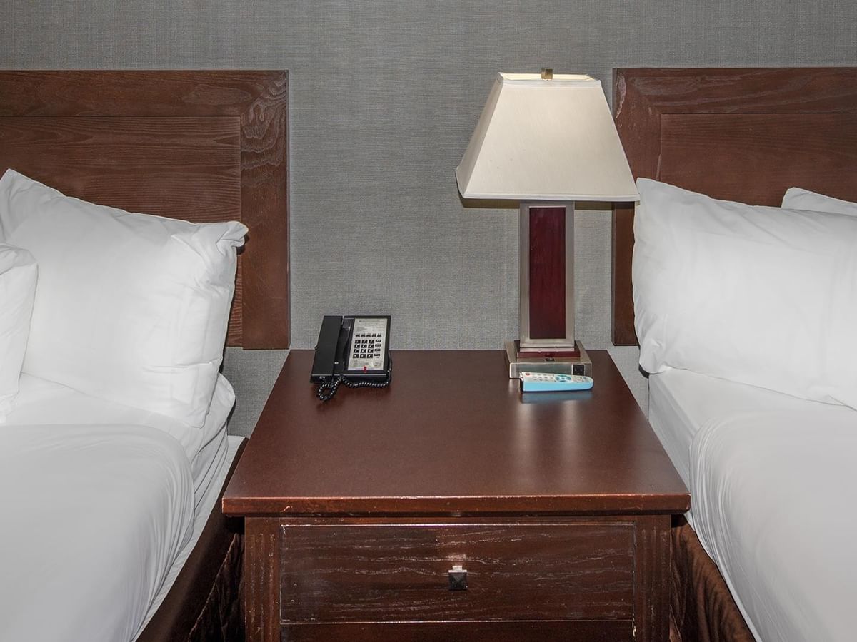 Two double beds with nightstand and lamp.