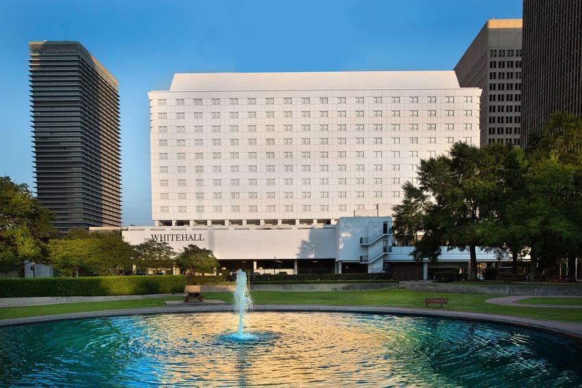 The Whitehall Houston’s white facade, viewed from the nearby park with its vibrant fountain