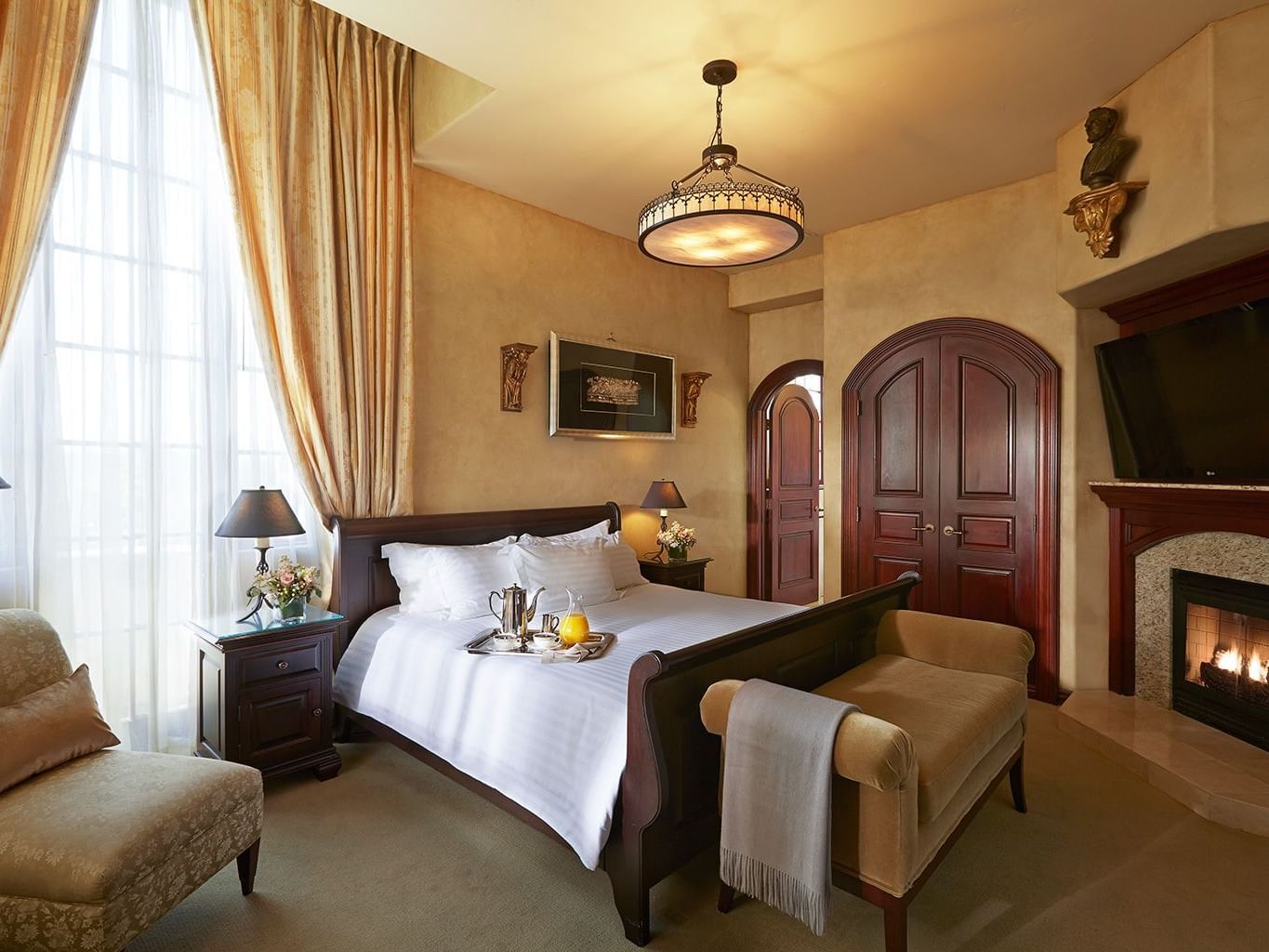 large room with king bed, footbench and fireplace