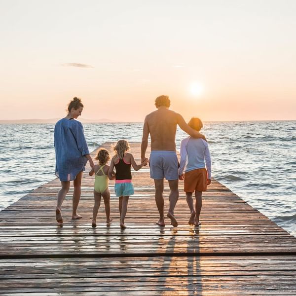 A family enjoying the sunset walking in a deck by sea  at Falkensteiner Hotels & Residences