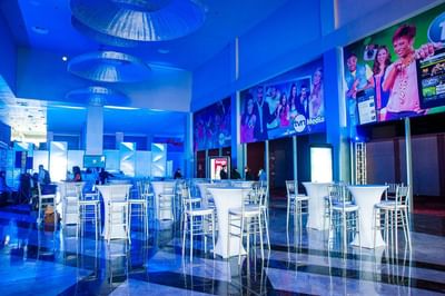 Tall white cocktail tables with tall chairs arranged in a modern hall under lighting at Megapolis Hotel Panama