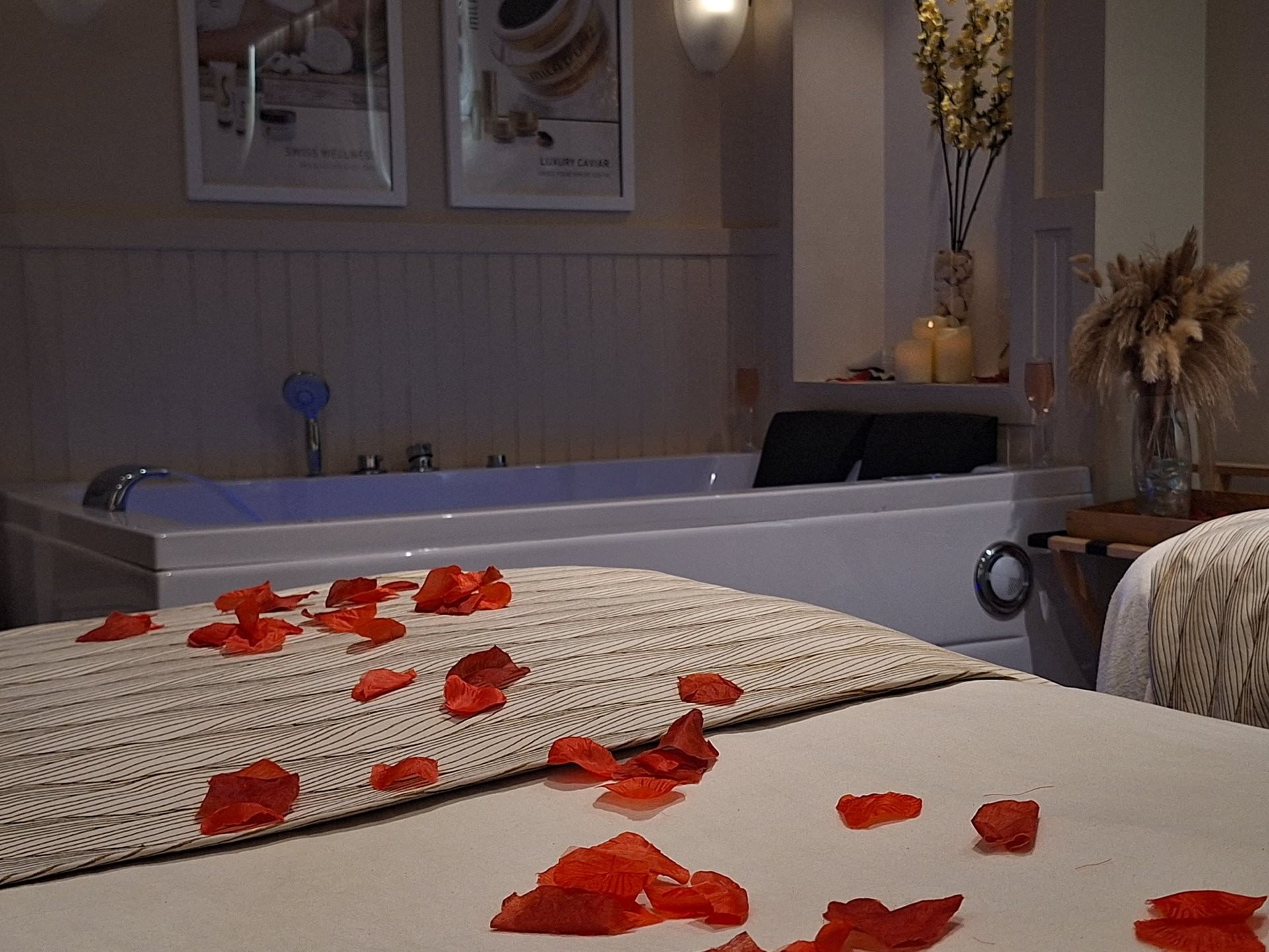 Massage table with red petals by a white soaking tub under soft ambient light at Warwick Paradise Island Bahamas