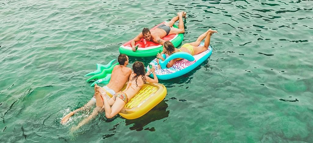 Four friends relaxing on inflatable tubes while floating down a river