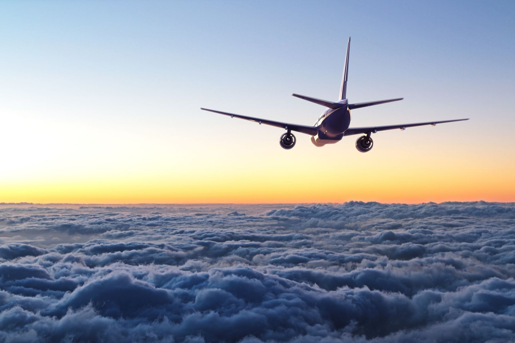 Airplane over clouds with sunset in background