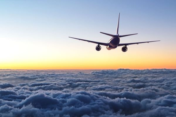 Airplane flying above clouds with sunset in background