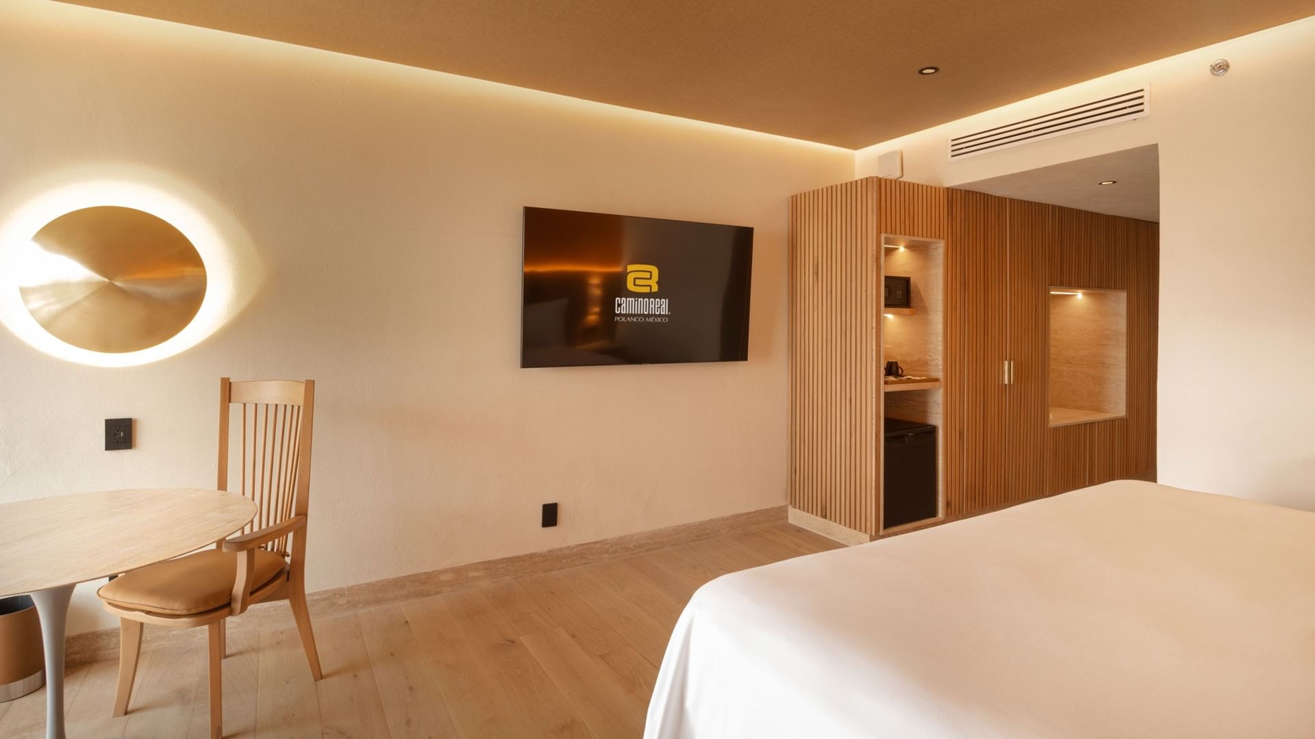 King Superior Camino Real Club showing a wall-mounted TV, wooden wardrobe, and a dining chair at Camino Real Polanco Mexico