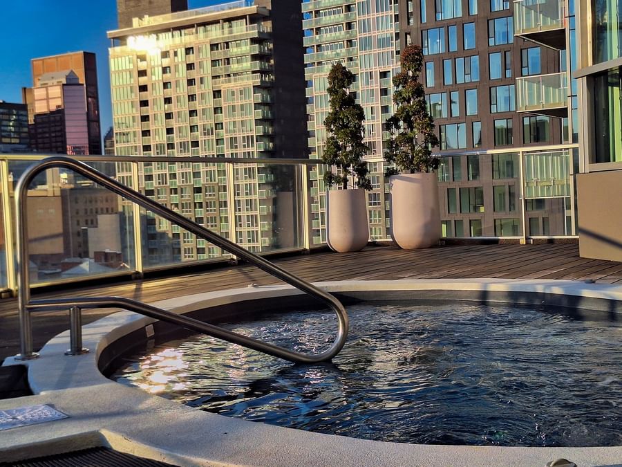 Rooftop hot tub on a wooden deck with a scenic city skyline view at Warwick Le Crystal Montreal