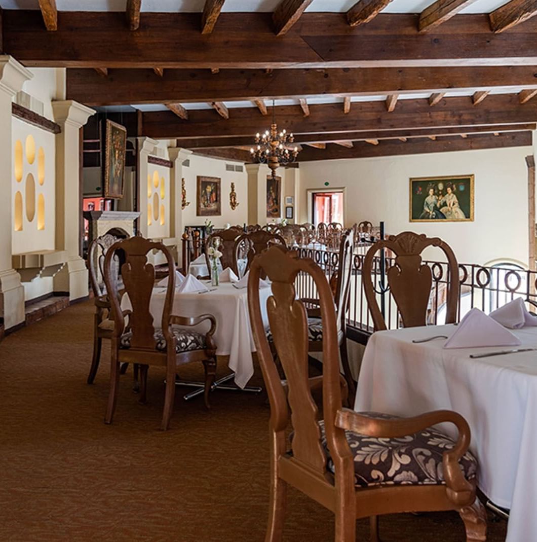 Tierra Mia restaurant with white tablecloths, ornate chairs, and rustic ceiling beams at Quinta Real Zacatecas