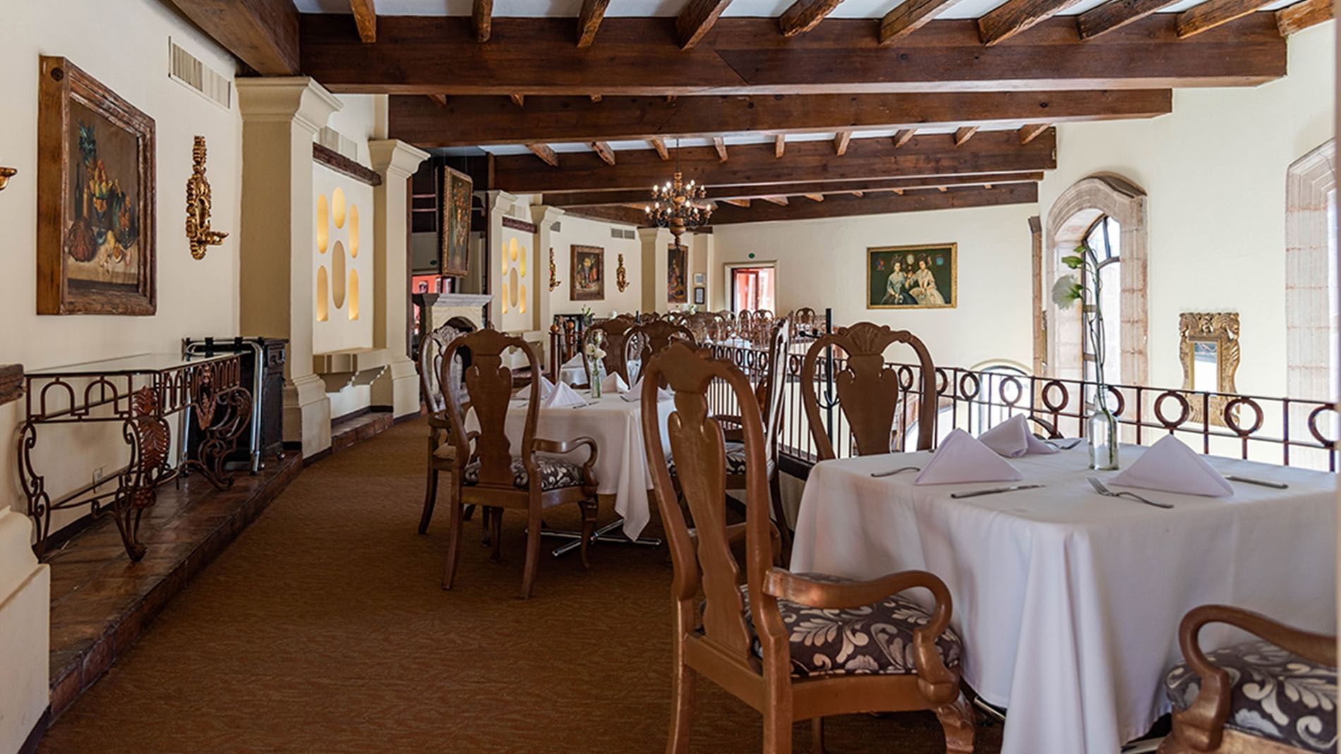 Tierra Mia restaurant with white tablecloths, ornate chairs, and rustic ceiling beams at Quinta Real Zacatecas