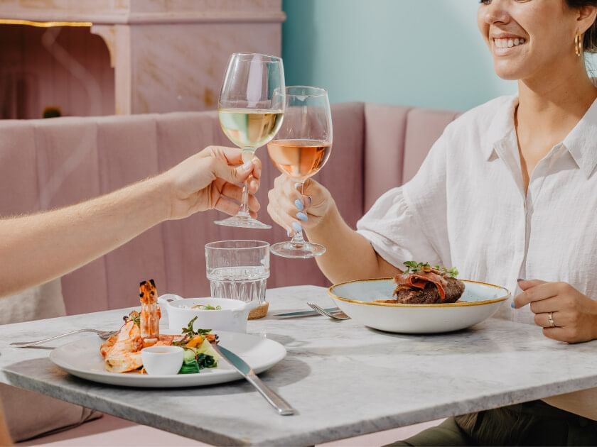 A couple cheering with wine served with dishes in the restaurant at The Magnolia Hotel