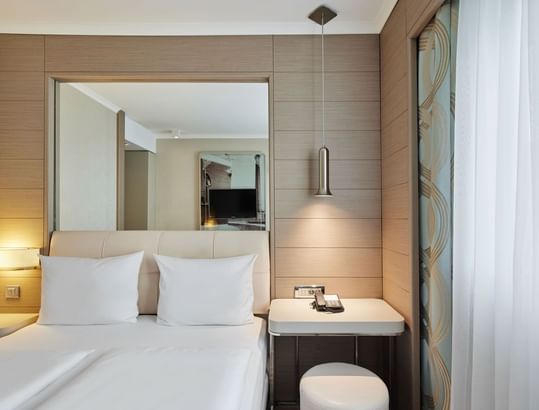 Business-Zimmer mit Queensize-Bett, Hängelampe und Spiegel über dem Schreibtisch im Titanic Comfort Mitte