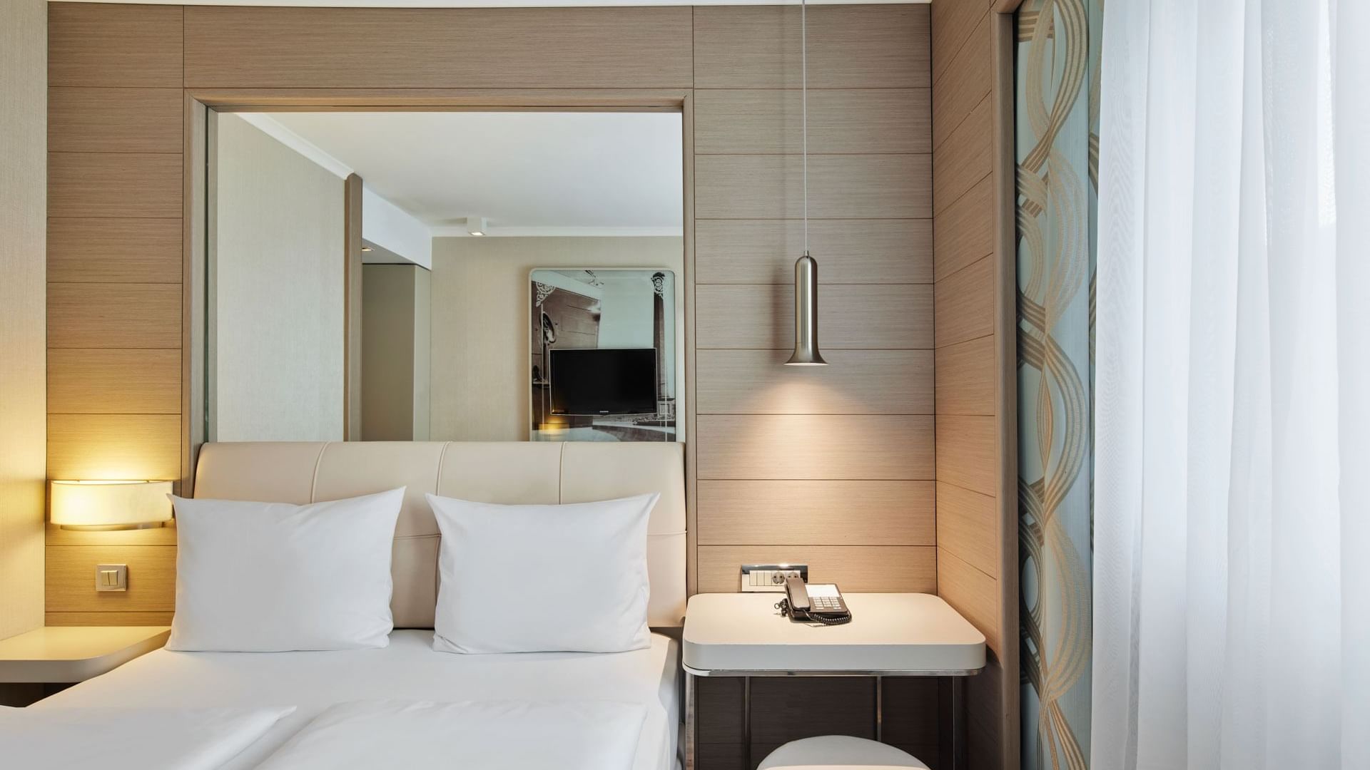 Business Room with a queen bed, pendant light and mirror over a desk at Titanic Comfort Mitte