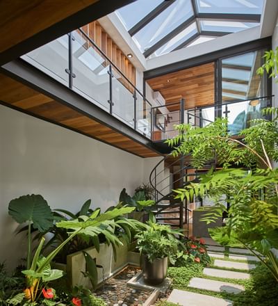 Stylish courtyard with a spiral staircase, a glass ceiling, and a lush garden in Casa Cielo at Singular Signature Residences