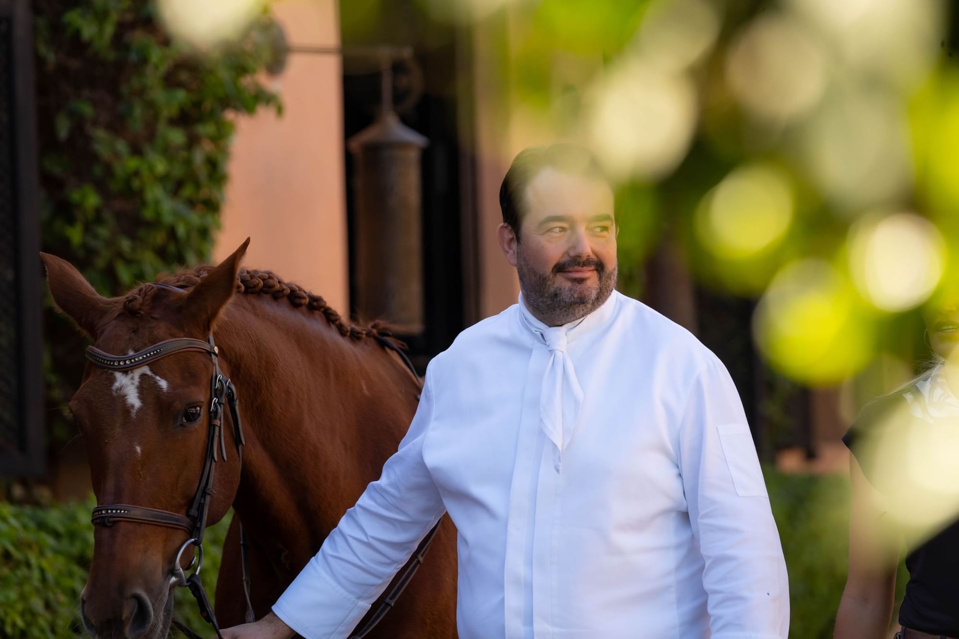Chef, Jean-François Piège in a white suit escorting a horse at Selman Marrakech