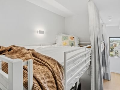 White bunk bed with curtains and cozy bedding in a clean room at UniLodge Brisbane City.