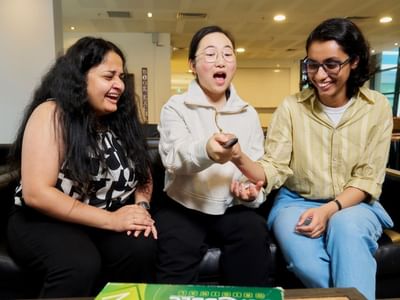 Three residents laughing and playing a board game at Student Living - 800 Swanston.