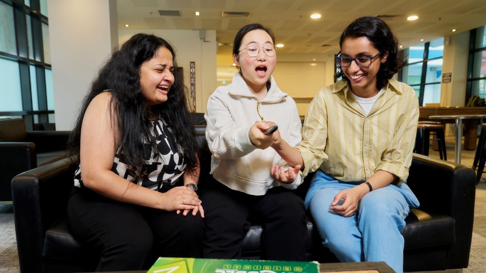 Three residents laughing and playing a board game at Student Living - 800 Swanston.
