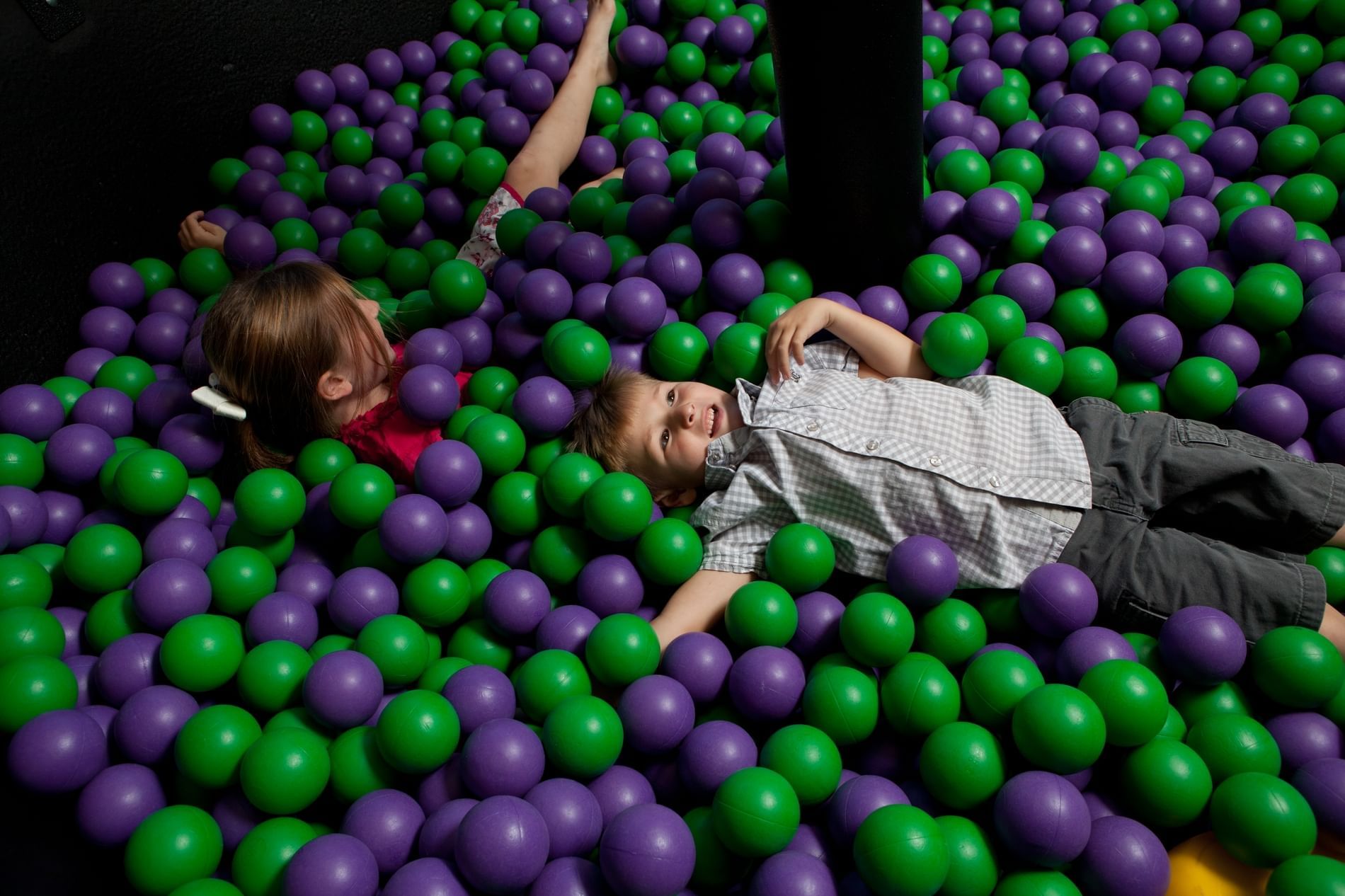 Lorem ipsum Two kids playing in green and purple ball pit