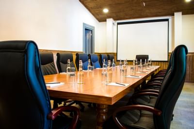 Leather chairs by a long wood table under a projector screen in Merlot Salon at NOI Blend Colchagua, Valley