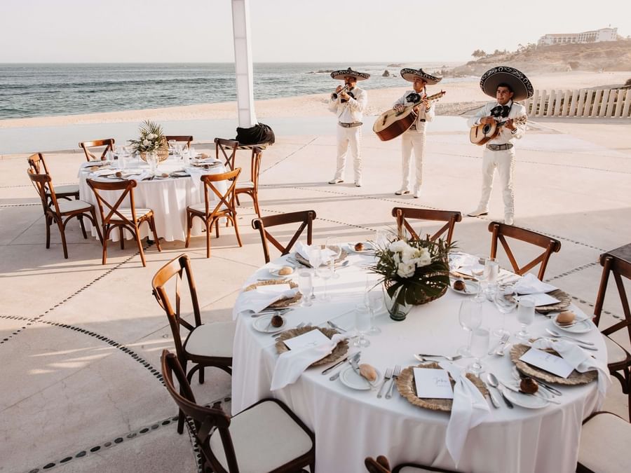 An elegant ballroom set up for an event, featuring chandeliers and decorated tables at Marquis Los Cabos Resort