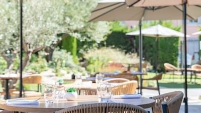 Terrasse d'un restaurant en plein air avec parasols, tables, chaises et verres d'eau.