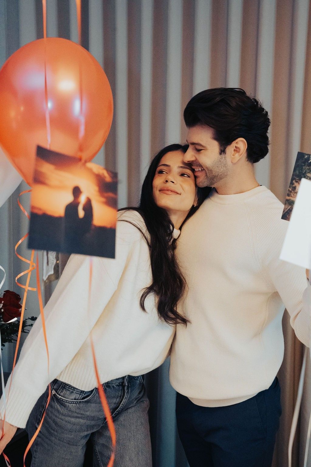 Couple embracing by hanging orange balloons and printed photos on ribbons at Hotel X Toronto