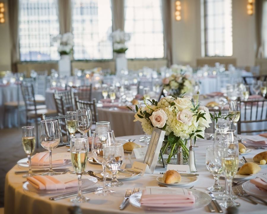 Round dining table with champagne glasses, floral centerpiece, and pale pink napkins at Warwick Allerton Chicago