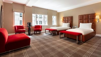 Spacious Accessible Room at The May Fair Hotel with two large beds, red accents, red chairs, and large windows