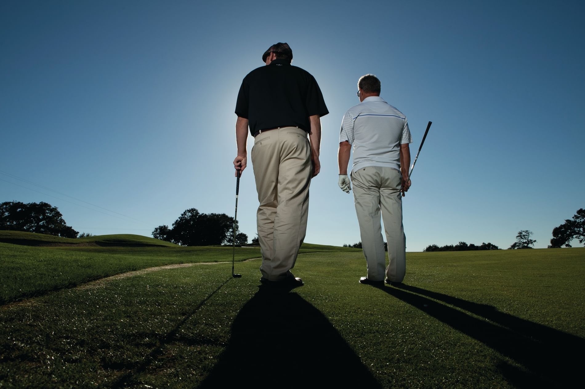 Two men standing on the fairway playing golf.  Blue sky and sunn