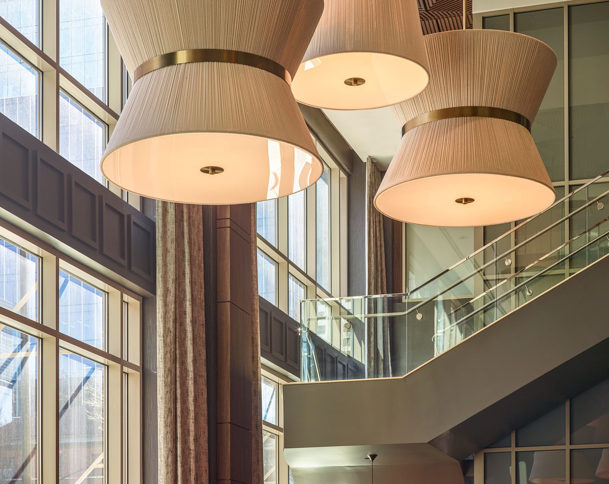 A modern lobby with a staircase, high ceilings, and large windows.