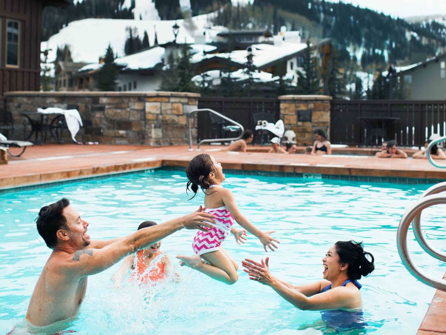 A family enjoying in the pool and winter scenery behind at The Chateaux Deer Valley