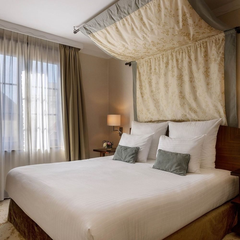 Draped bed between the side tables near the window in Premium Room at Warwick Grand Place Brussels