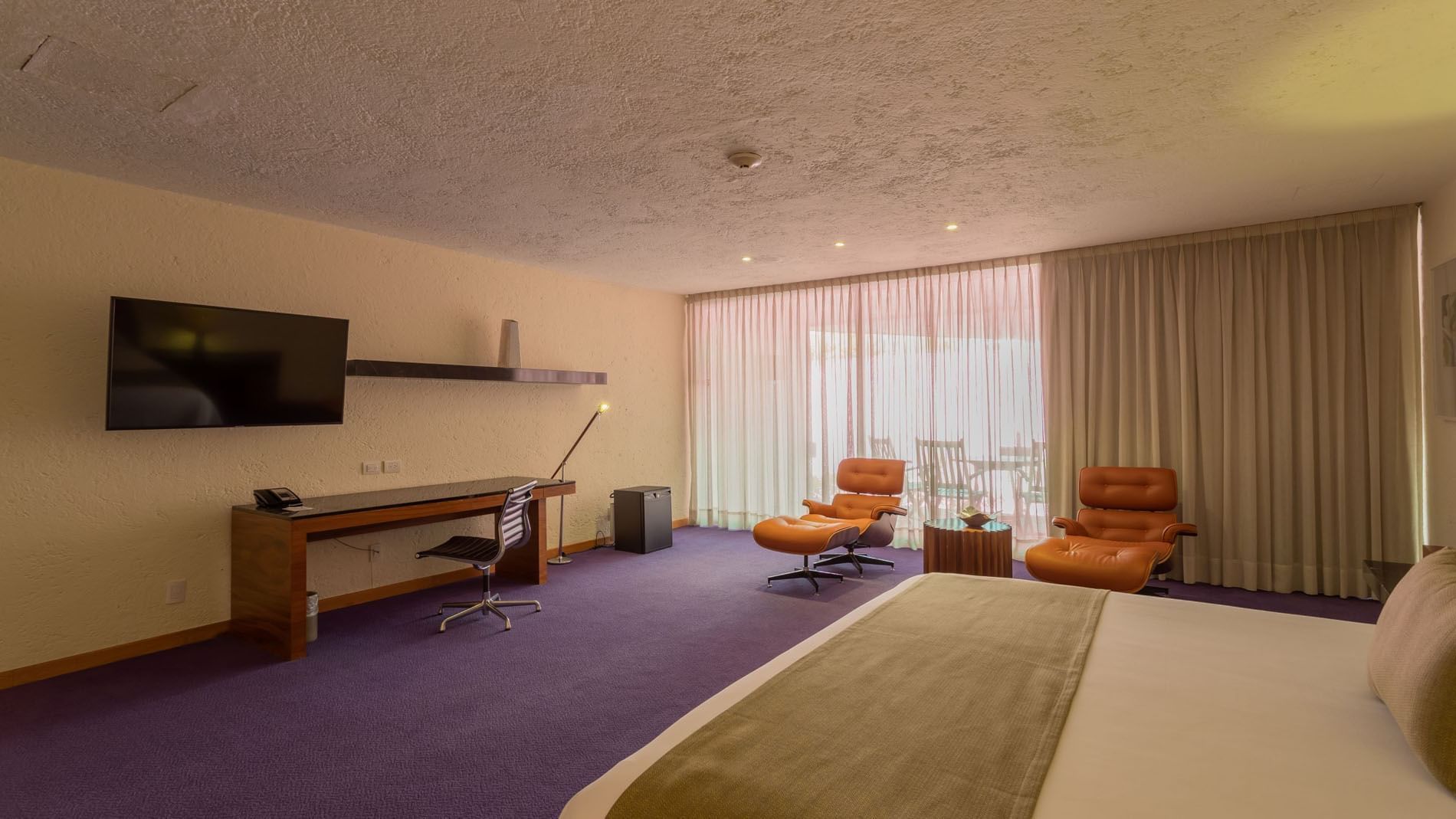 King Chapultepec Suite with purple floors, two orange chairs, and large window curtains at Camino Real Polanco Mexico