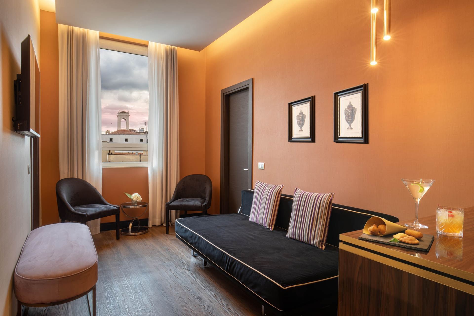 Stylish room at The Guardian Hotel with orange walls, modern furniture, a cozy sofa, and a skyline view through the window