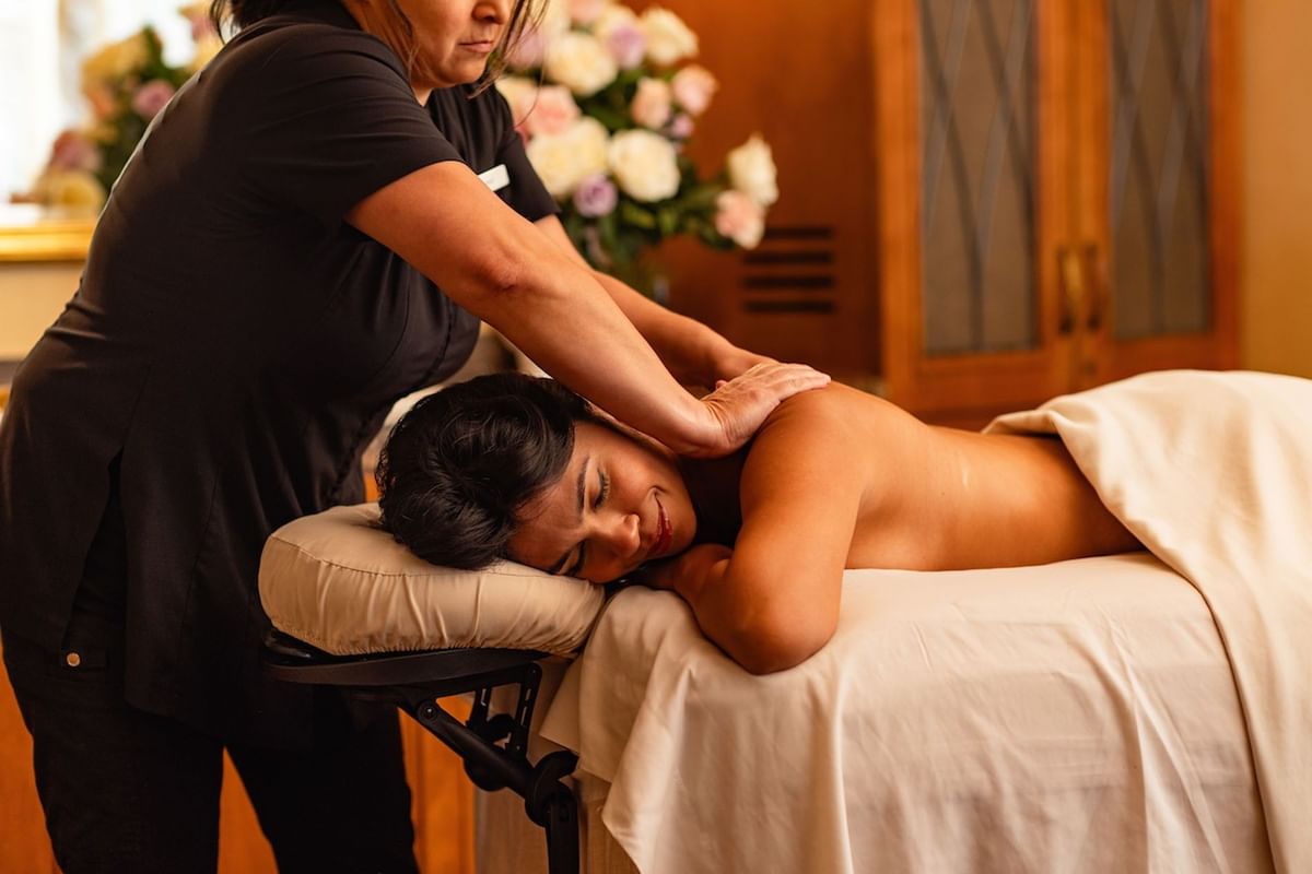 Massage therapist performing Fountain of Youth Signature Treatment on a woman in a serene, upscale spa setting at Kelly's Spa