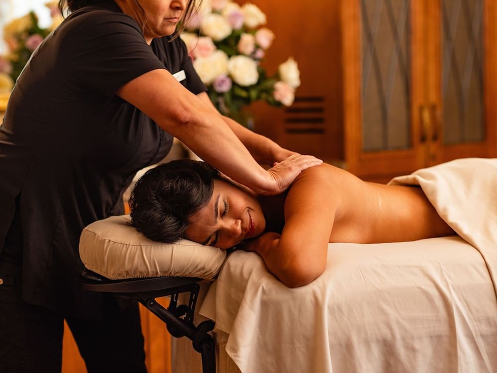 Massage therapist performing Fountain of Youth Signature Treatment on a woman in a serene, upscale spa setting at Kelly's Spa