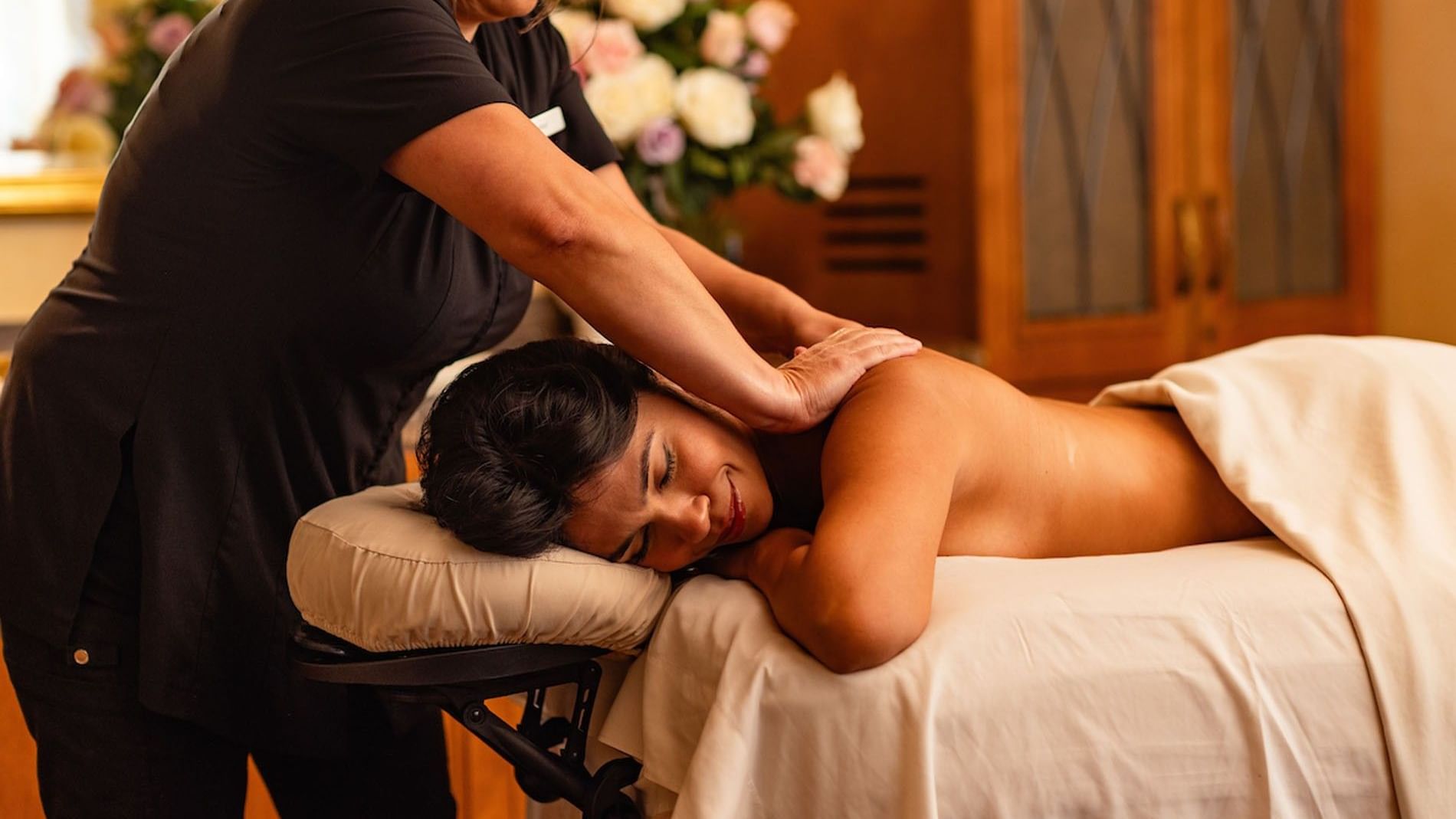 Massage therapist performing Fountain of Youth Signature Treatment on a woman in a serene, upscale spa setting at Kelly's Spa