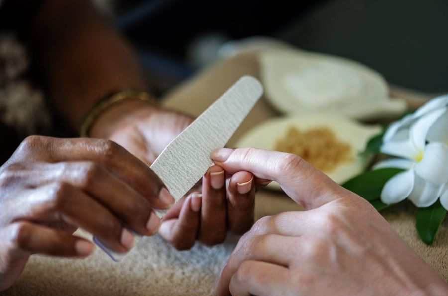 Therapist filing a guest's nails by a white flower under soft lighting at The Naviti Resort - Fiji