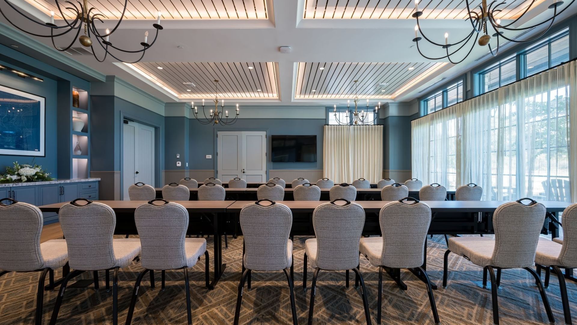 Club Room with upholstered chairs around dark tables, teal walls, and wood-paneled ceiling at Camp Creek Inn, Inlet Beach.